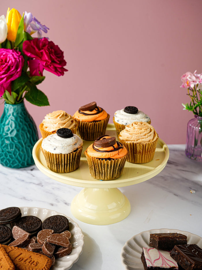 Biscoff, cookies and chocolate orange cupcakes on a cake stand with biscuits and brownies