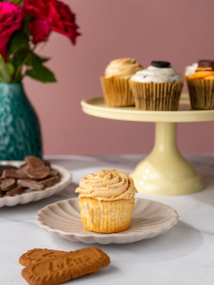 Biscoff cupcake topped with caramel buttercream beside a Lotus biscuit