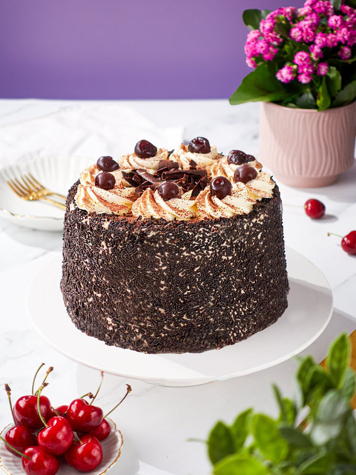 Side view of the Black Forest Gateau showing its chocolate flake coating and cherry topped cream