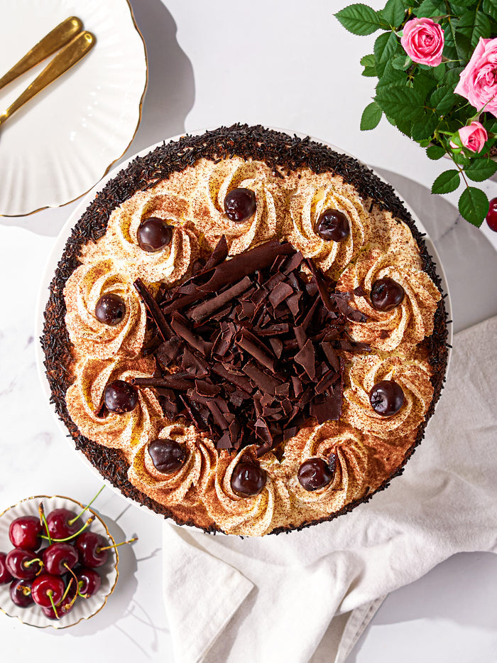 Overhead view of a Black Forest Gateau, cream rosettes and cherries ringing a pile of chocolate curls