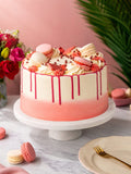 Blush Pink Celebration Drip Cake with a raspberry drip, macarons and piped cream on top