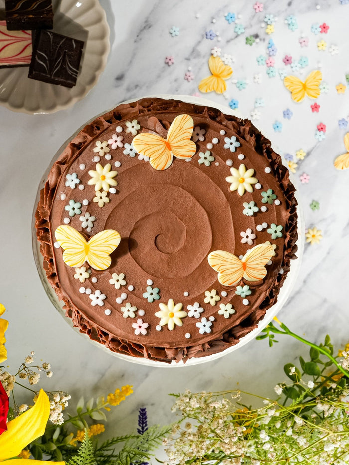 Overhead view of the Chocolate Forest Fantasy Cake, butterflies and blossoms set on swirled chocolate