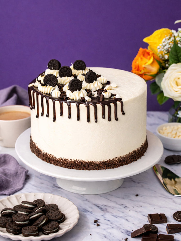 Cookies and Cream Cake with a chocolate drip and cream filled biscuits piled on top