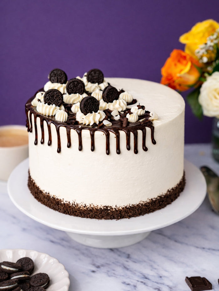 Whole Cookies and Cream Cake with chocolate drip running down its vanilla buttercream sides