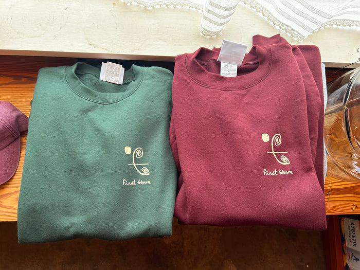 Folded crew First Bloom sweatshirts in sage and maroon