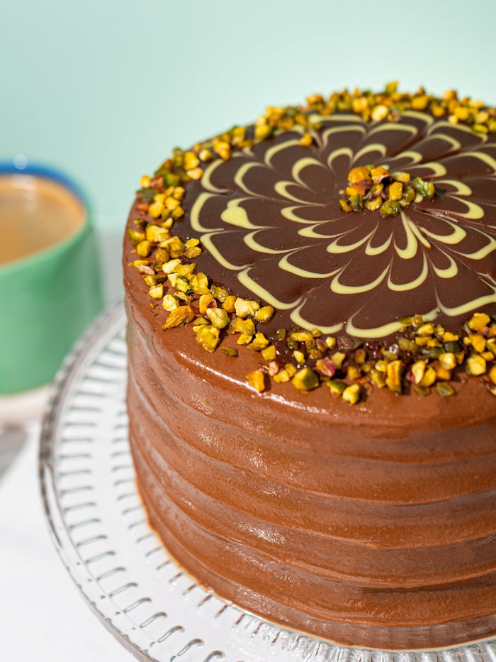 Close view of the feathered chocolate glaze and chopped pistachio ring on top of the cake