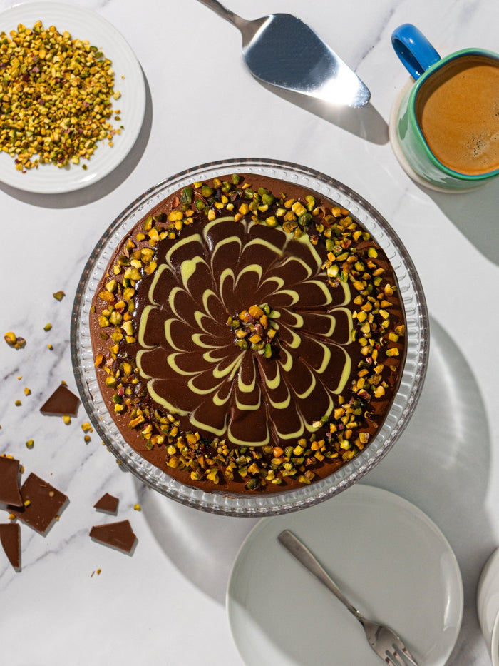 Overhead view of the Dubai style chocolate cake, feathered glaze ringed with chopped pistachio