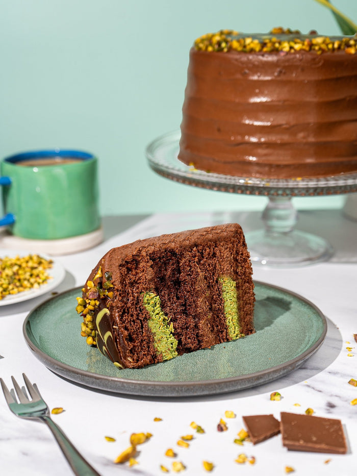 Slice of Dubai style chocolate cake showing the bright pistachio filling in chocolate sponge