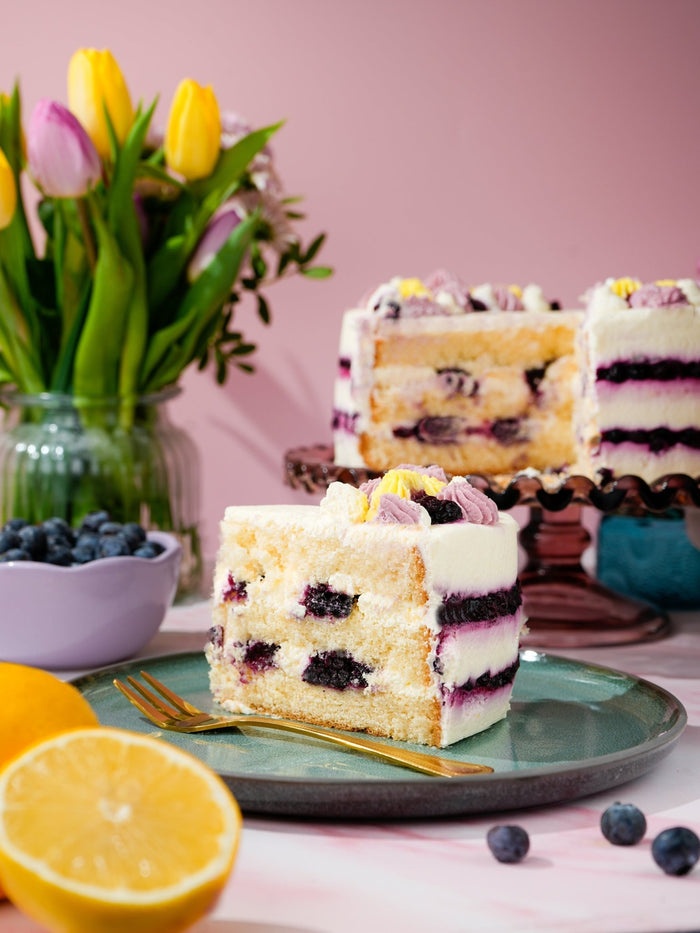 Slice of lemon and blueberry cake showing blueberries and citrus cream between light sponge layers