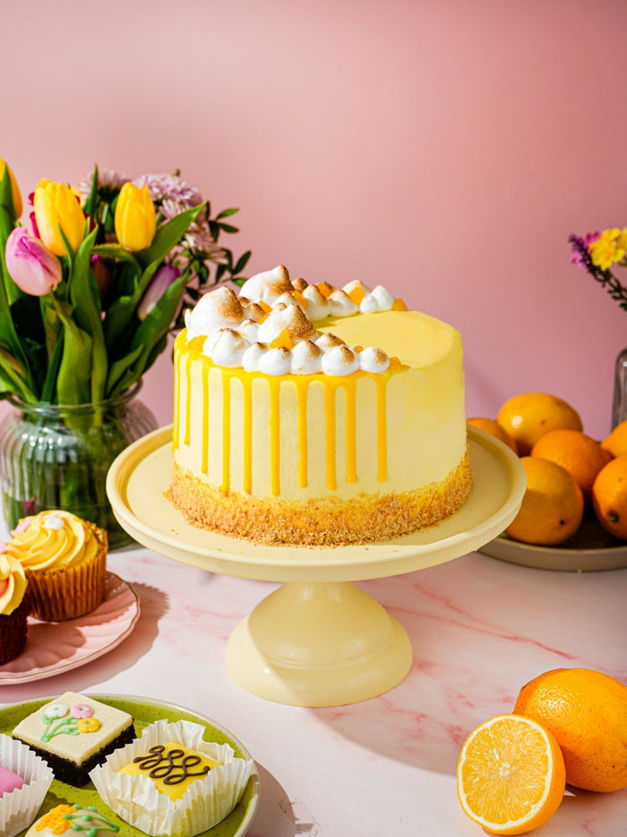 Lemon Meringue Magic Cake with lemon curd drip and toasted meringue kisses on top