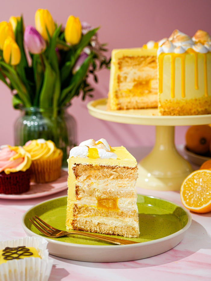 Slice of lemon meringue cake showing lemon curd between soft sponge layers