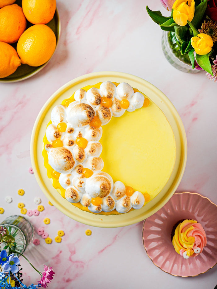 Overhead view of the lemon meringue cake, toasted meringue kisses curving over the lemon topping