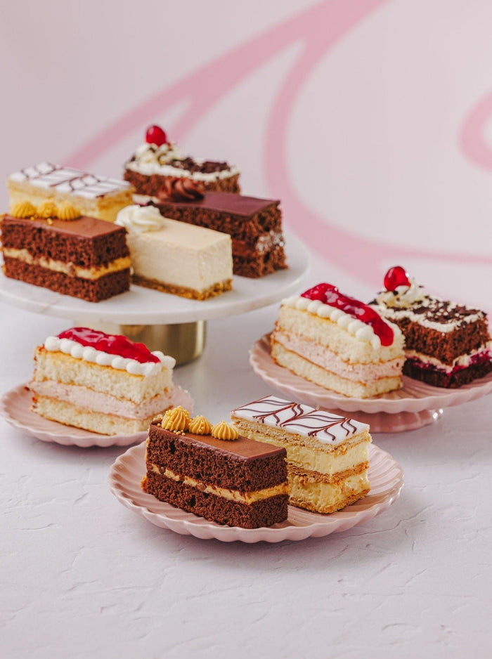 Ten assorted cake slices arranged on cake stands and plates ready to pick and mix
