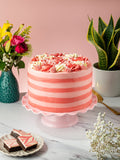 Pink Candy Stripe Gateau on a pink cake stand with fresh flowers and a plate of brownies