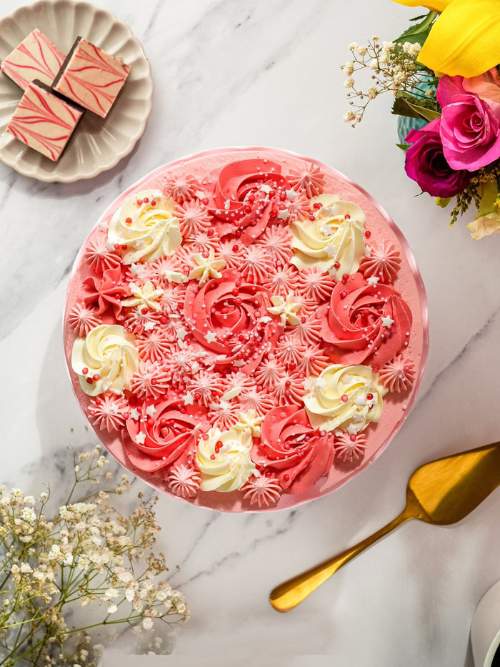 Overhead view of the piped pink and cream rosettes and sprinkles on top of the candy stripe cake