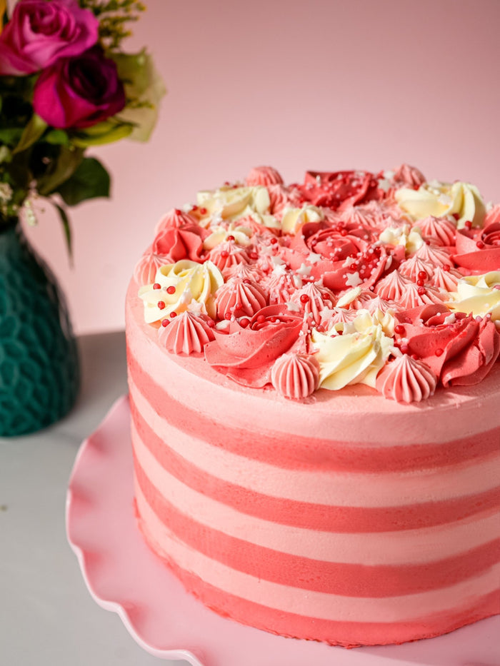 Close view of the pink candy stripe buttercream and piped rosettes on this pink birthday cake