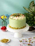 Pistachio and Raspberry Delight Cake in green buttercream with a chopped pistachio base