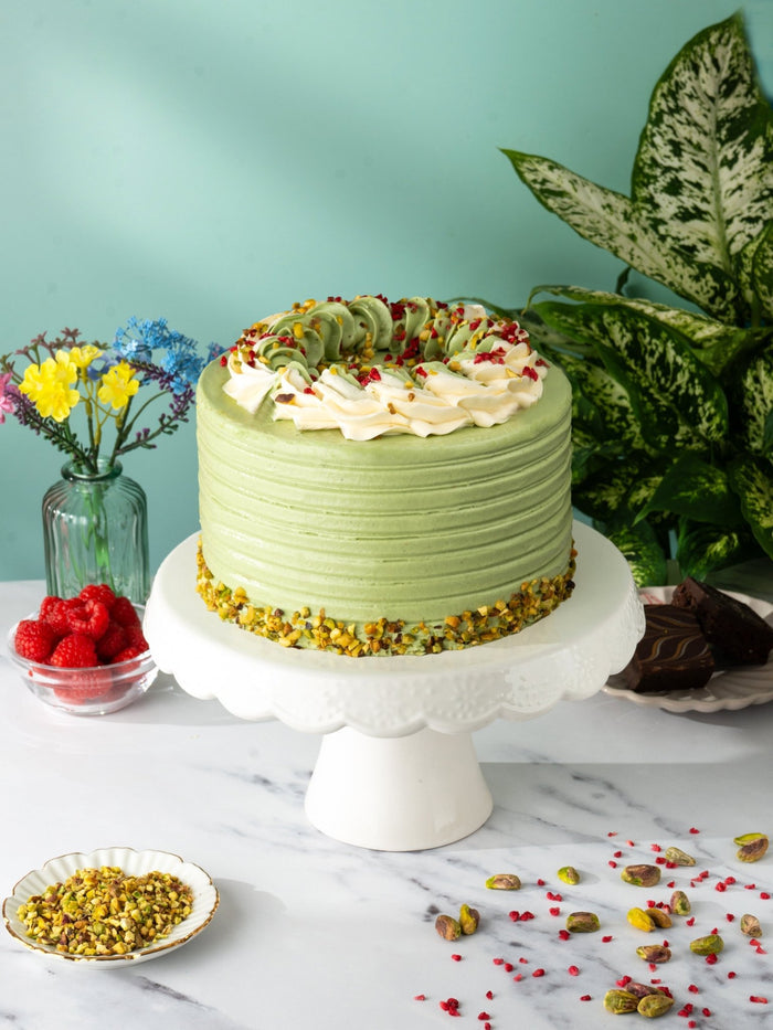 Pistachio and Raspberry Delight Cake in green buttercream with a chopped pistachio base