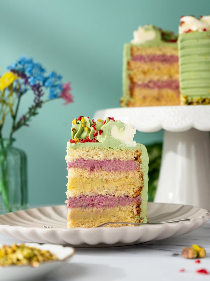Slice of pistachio and raspberry cake showing green pistachio cream and raspberry between sponge