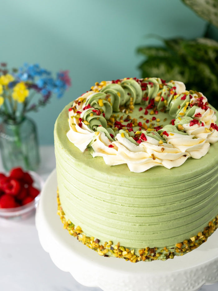 Close view of the piped cream and chopped pistachio crowning the pistachio and raspberry cake