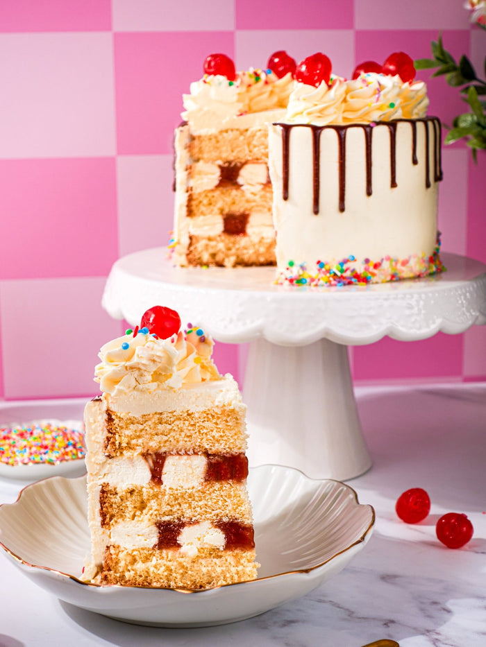 Sweet Treat Sundae Cake cut open with a slice plated, showing sponge, cream and jam layers