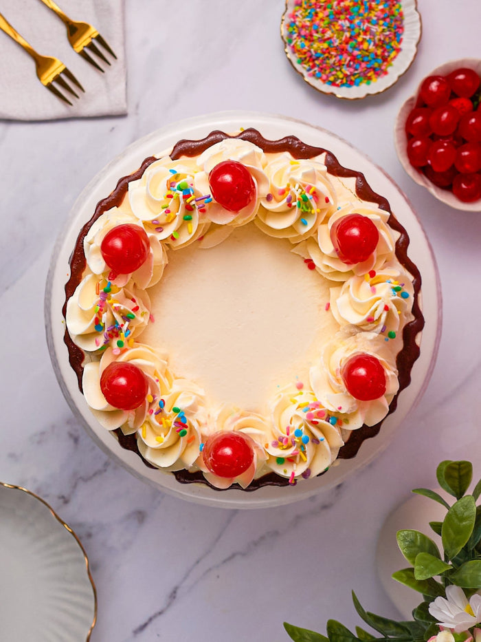 Overhead view of the sundae cake, cream swirls, cherries and sprinkles around a plain centre