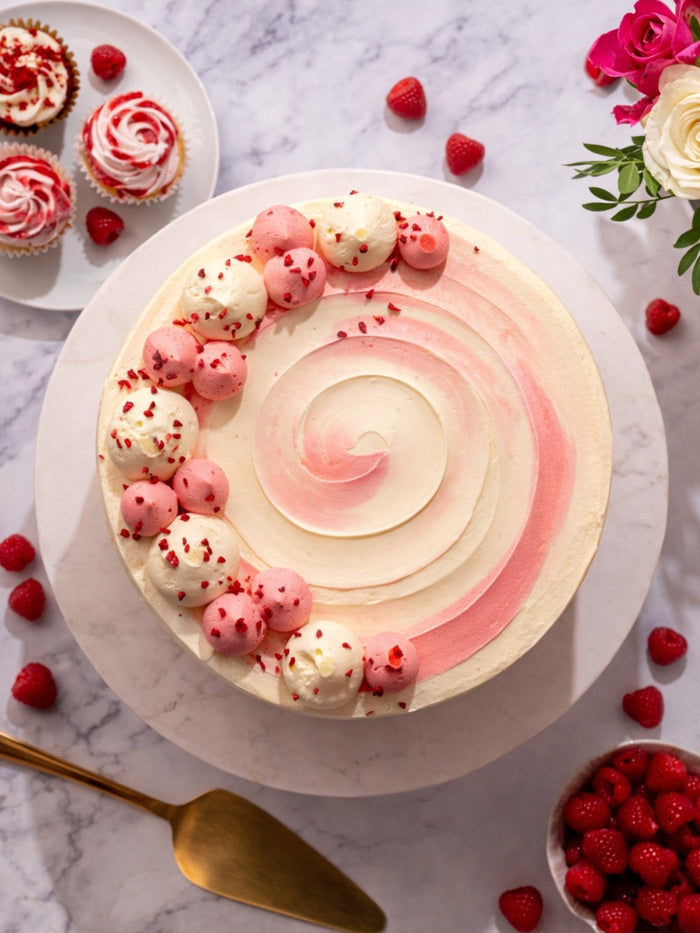 Overhead view of the raspberry ripple swirl and piped pink and white domes on top of the cake