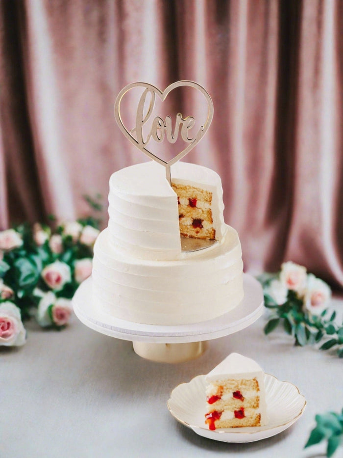 Two tier wedding cake with a slice plated in front, showing the strawberry and cream filling