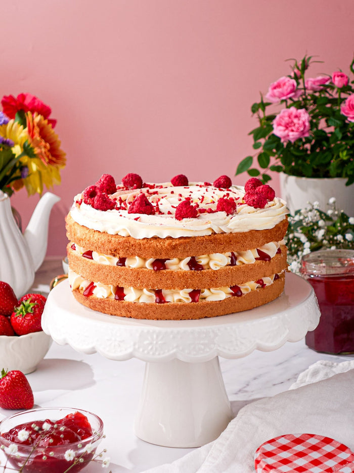 Victoria Sponge Cake layered with cream and strawberry jam, fresh raspberries on top
